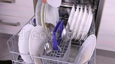 男人`手在洗碗机里放一个白色的<strong>脏盘子</strong>和勺子，然后在厨房里运行。